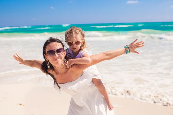 Young beautiful mother and adorable little daughter spread her arms like a bird on white beach — Stock Photo, Image