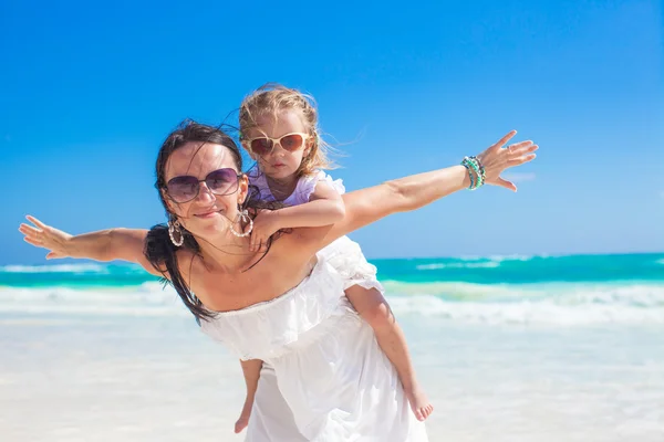 Young beautiful mother and her adorable little daughter flying like a bird at tropical beach — Stock Photo, Image