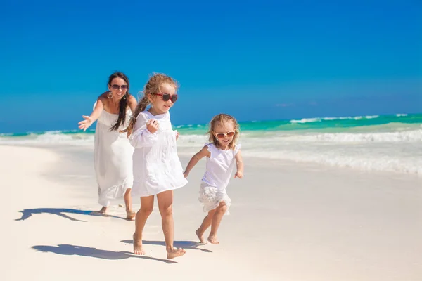 Joven madre feliz y sus adorables hijas se divierten en la playa exótica en el día soleado — Foto de Stock