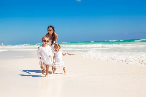 Молодая мать и ее маленькие дочери прогуливаются по тропическому белому пляжу — стоковое фото