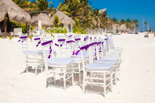 Sedie da sposa bianche decorate con fiocchi viola sulla spiaggia di sabbia — Foto Stock