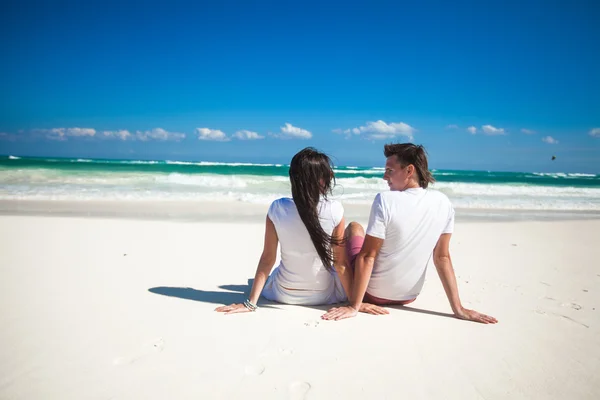 Back view of young couple in love sitting at tropical white beach — Stock Photo, Image