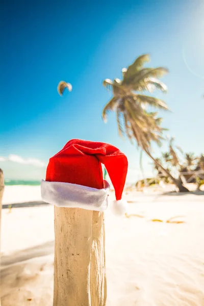 圣诞老人的帽子，在白色的沙滩在阳光灿烂的日子 — 图库照片