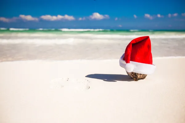 Kerstman hoed op kokosnoot op een wit zandstrand — Stockfoto