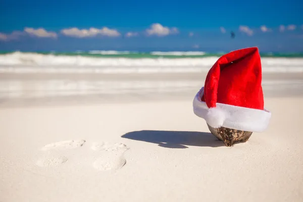 Jultomten hatt på coconut på en vit sandstrand — Stockfoto