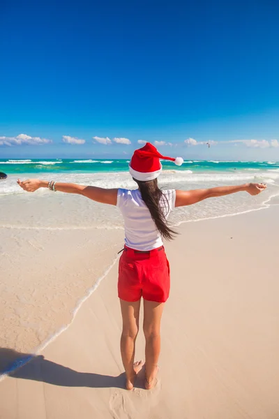 Young woman in Santa Hat walking spread her hands on white sandy beach — Stock Photo, Image