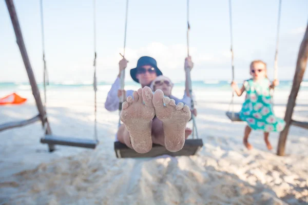 Ung mamma och hennes söta dotter svänga på en gunga på stranden — Stockfoto