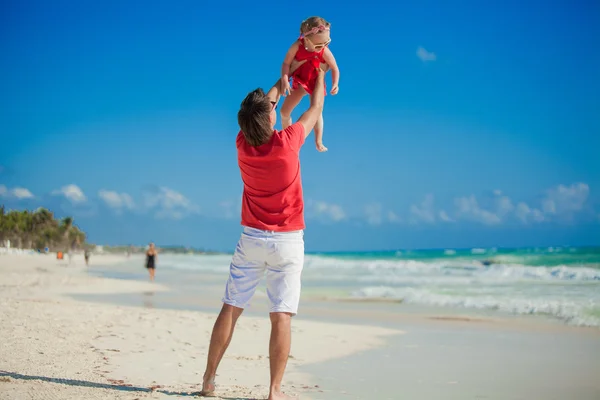Joven padre feliz y su pequeña hija se divierten en la playa blanca en el día soleado — Foto de Stock