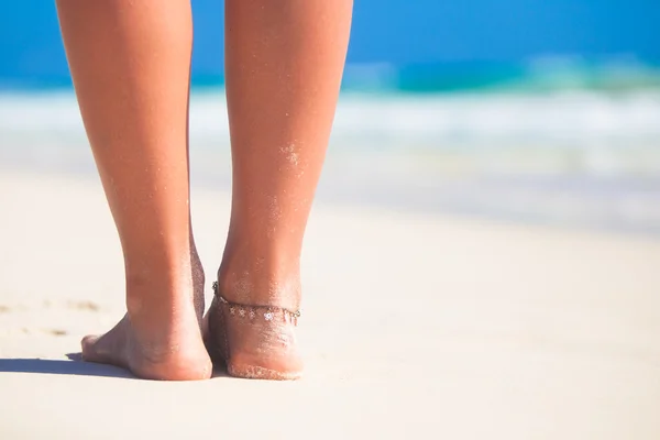 Krásné dámské hladké nohy na pláži s bílým pískem — Stock fotografie