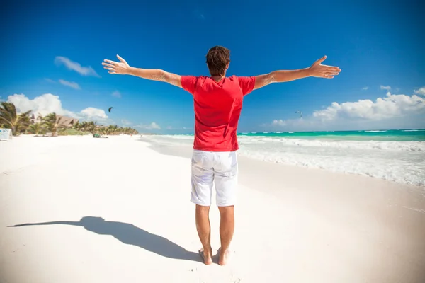 Rückansicht eines jungen Mannes, der den Urlaub genießt, breitet seine Hände am tropischen Strand aus — Stockfoto
