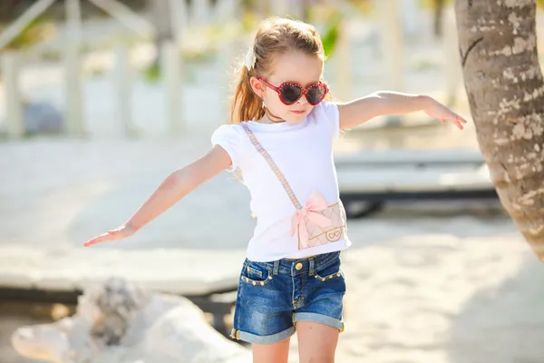 Adorable happy smiling little girl on beach vacation walks squaring arm — Stock Photo, Image