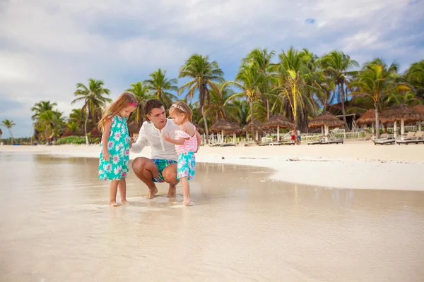 Pai e suas adoráveis filhas brincando na praia — Fotografia de Stock