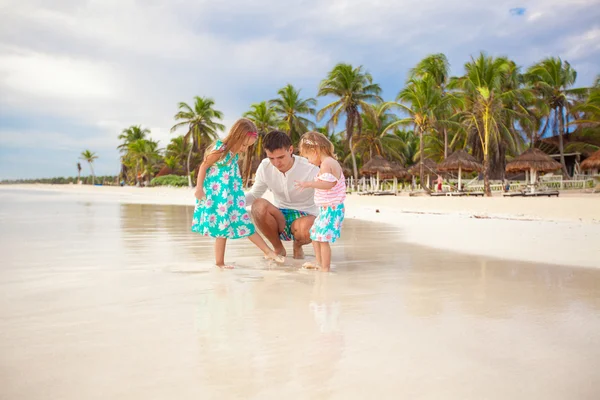 Far och hans bedårande lilla döttrar spelar på stranden — Stockfoto