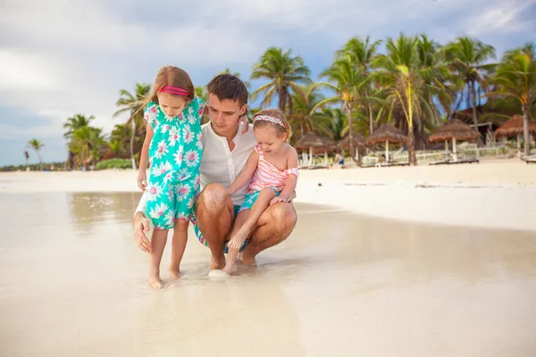 Gelukkig vader en zijn schattige kleine dochters spelen op het strand — Stockfoto