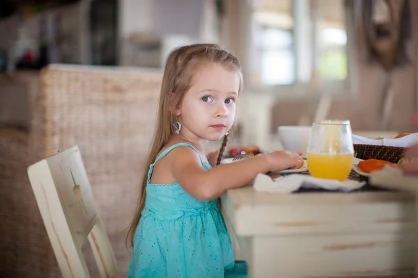 Adorable little girl having breakfast at resort restaurant — Stock Photo, Image