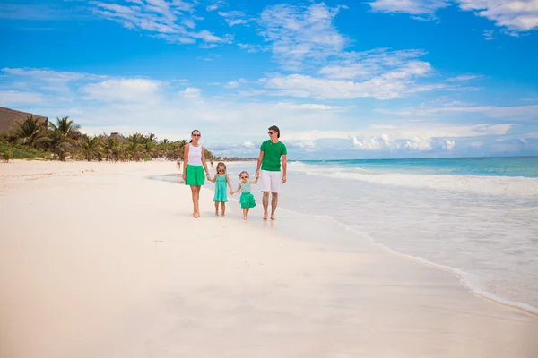 Jovem bela família de quatro caminhando na praia de areia branca — Fotografia de Stock