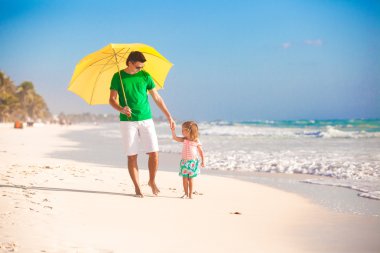 genç Baba ve küçük kızı sarı bir şemsiye altında yürüyüş