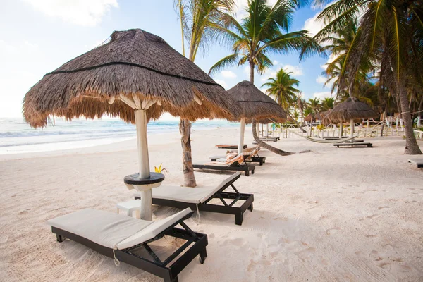 Chaise lounges under an umbrella on white sandy beach — Stock Photo, Image