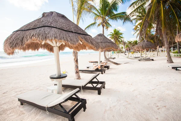 Chaise salones bajo un paraguas en la playa de arena —  Fotos de Stock