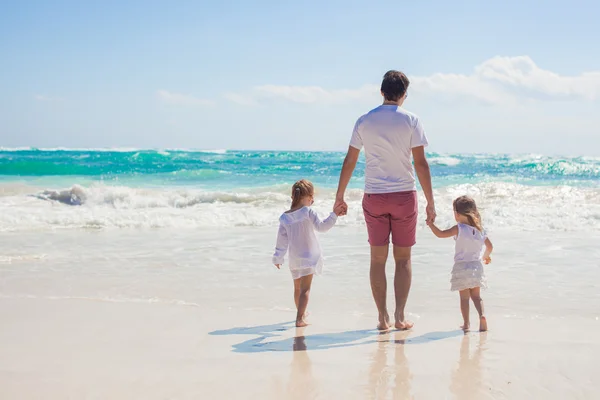 Bakifrån av unga far och hans bedårande lilla döttrar går på vit sandstrand i solig dag — Stockfoto