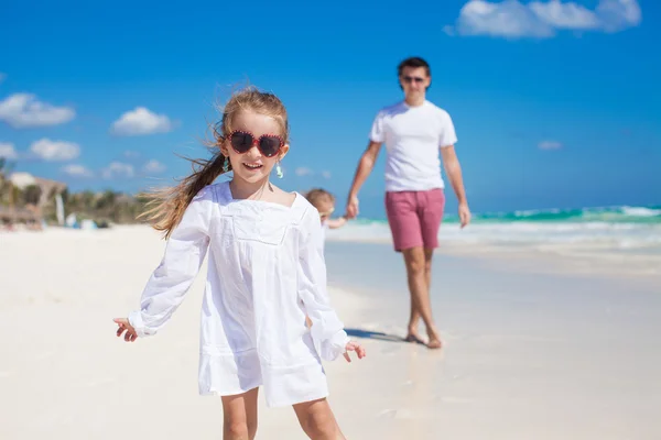 Menina se divertindo com sua irmã bonito e jovem pai na praia de areia branca — Fotografia de Stock