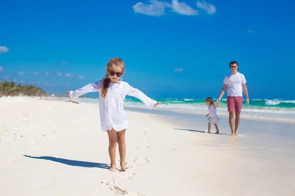 Little girl having fun with her cute sister and young father on white sand beach — Stock Photo, Image
