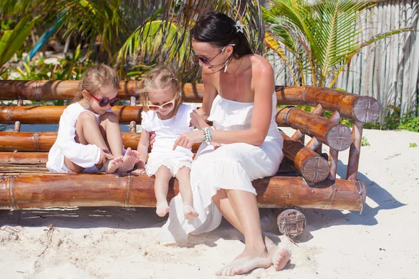 Jonge moeder met schattige dochters zitten in strandstoel en genieten van hun vakantie — Stockfoto