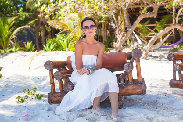 Young sexy woman sitting on wooden chair in exotic tropical resort — Stock Photo, Image