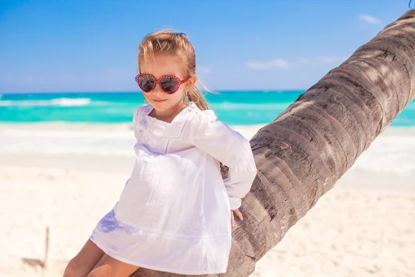 Retrato de una niña linda sentada en la palmera en la playa caribeña perfecta — Foto de Stock