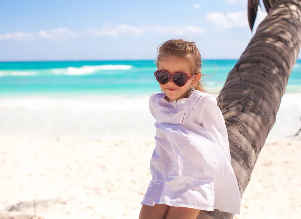 Retrato de una adorable niña sentada en la palmera en la playa caribeña perfecta —  Fotos de Stock