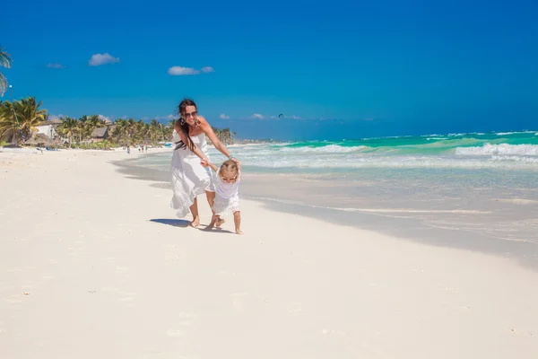 Милая забавная дочь развлекается со своей милой молодой матерью на белом песчаном пляже в Мексике — стоковое фото