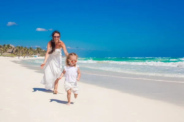 Niedlichen lustigen Tochter Spaß mit ihrer netten jungen Mutter auf dem weißen Sandstrand in Mexiko — Stockfoto