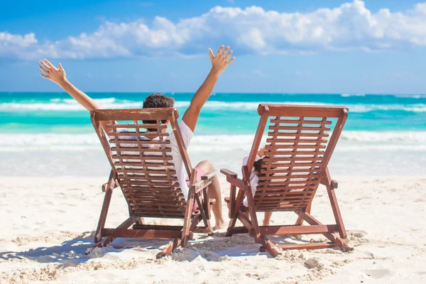 Young father with little daughter in beach chairs raised their hands up on shore ocean — Stock Photo, Image