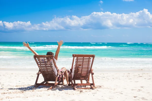 Jonge vader met dochtertje in strandstoelen opgewekt hun handen op de zee — Stockfoto