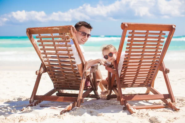 Young father and his wonderful daughter sitting on beach wooden chairs looking at camera — Stock Photo, Image