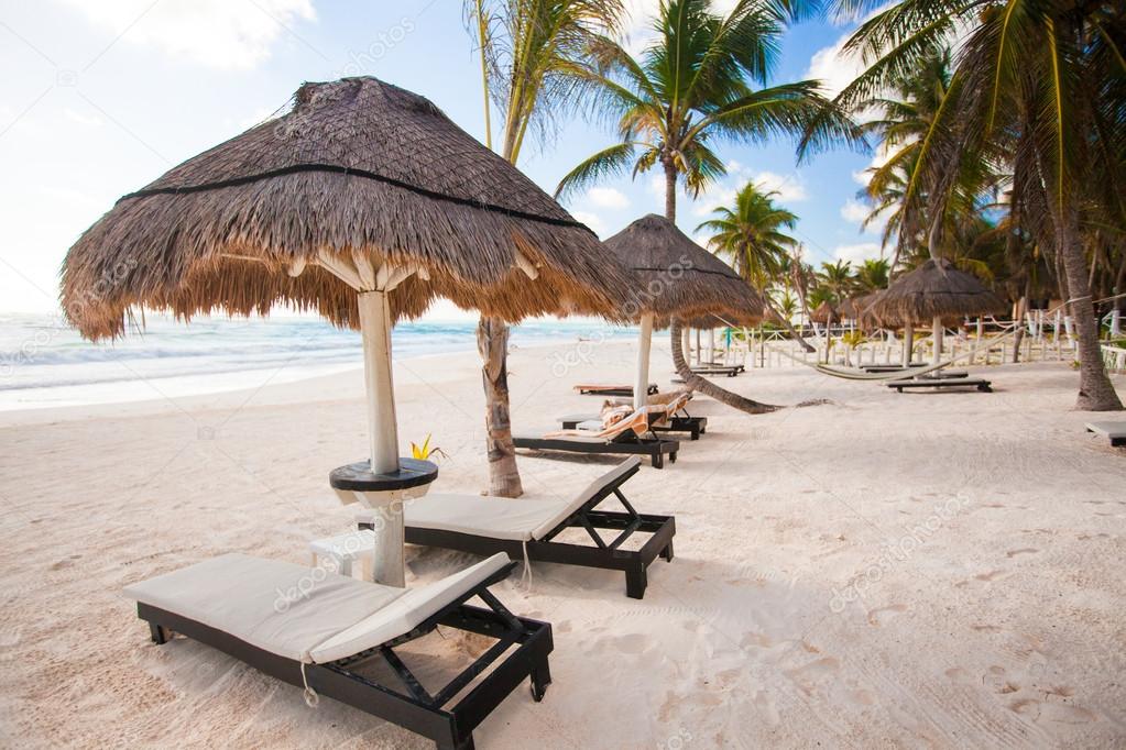 Chaise lounges under an umbrella on white sandy beach
