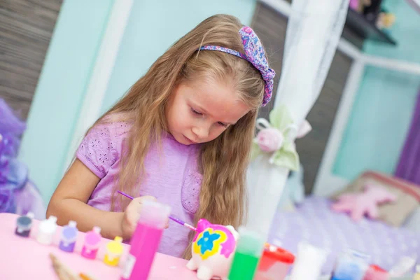 Little cute girl is painting with gouache while sitting at her table — Stock Photo, Image