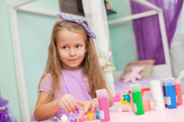 Adorable Little girl draws paints at her table in the room — Stock Photo, Image