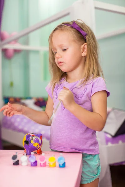 Adorable petite fille dessine des peintures assis à la table — Photo