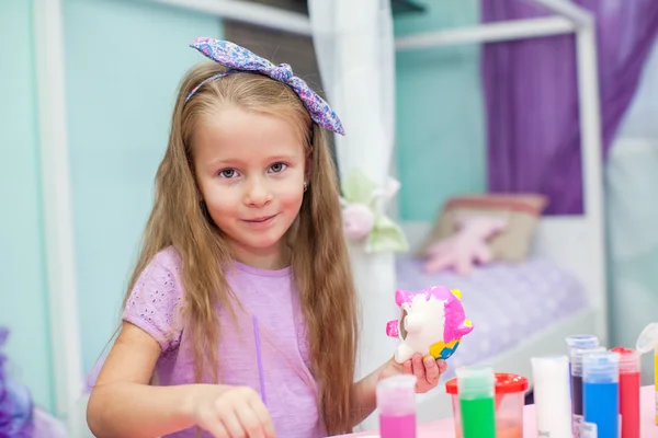 Petite fille mignonne dessine des peintures à sa table dans la chambre — Photo