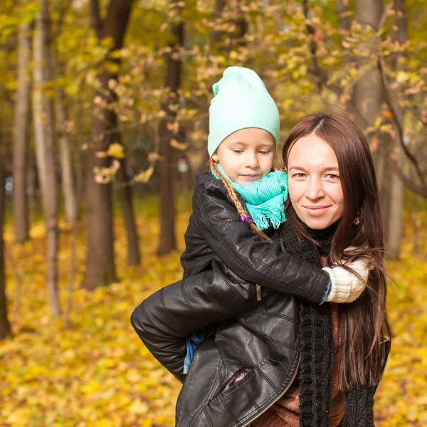 幸福的母亲和她可爱的女儿走在黄色秋天的树林在温暖的阳光灿烂的日子 — 图库照片