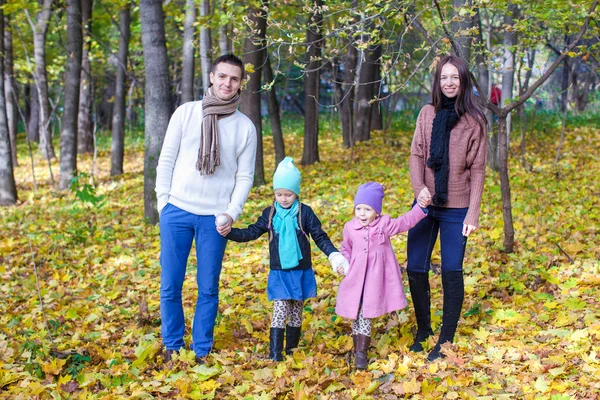 Family of four walk in autumn park on a sunny warm day — Stock Photo, Image