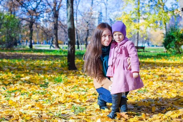 Liten söt flicka och ung mamma i höst park på solig dag — Stockfoto