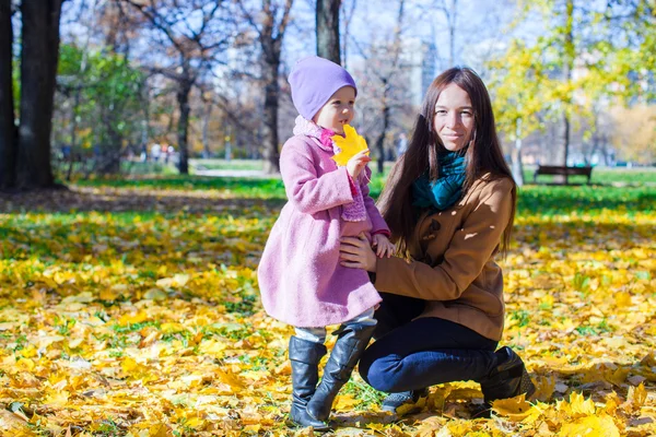 Lilla bedårande flicka och ung mamma i höst park på solig dag — Stockfoto