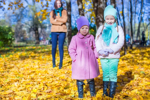 Two adorable girls with his young mom in the park on a sunny autumn day — Stock Photo, Image