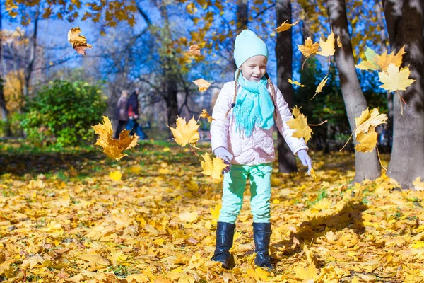 Little funny girl throws autumn leaves in park on fall day — Stock Photo, Image