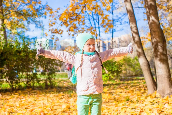 Little funny girl throws autumn leaves in park on fall day — Stock Photo, Image