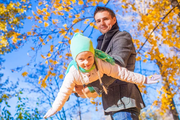 Niña linda con padre feliz divirtiéndose en el parque de otoño en un día soleado —  Fotos de Stock