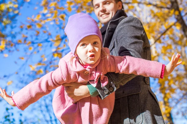 Menina adorável com pai feliz se divertindo no parque de outono em um dia ensolarado — Fotografia de Stock
