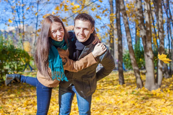 Young Couple having fun in autumn park on a sunny fall day — Stock Photo, Image